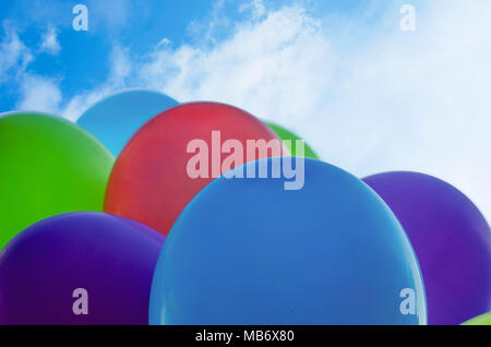 Colorful multicolored inflatable balls fly in air against background of tblue sky during festive. Multicolored balloons against the blue sky, close up Stock Photo
