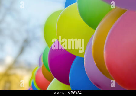Colorful multicolored inflatable balls fly in air against background of tblue sky during festive. Multicolored balloons against the blue sky, close up Stock Photo