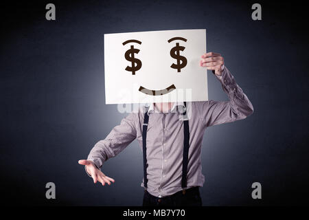 Young casual businessman hiding behind a greedy face drawing on cardboard Stock Photo