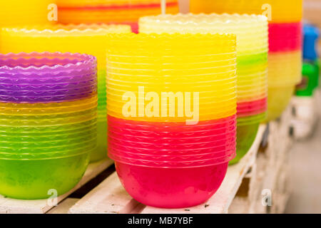 Plastic multi-colored bowls on the shelf in the store. Stock Photo