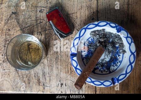 A glass of whisky, a cigar, a lighter and an ashtray on a table taken from above Stock Photo