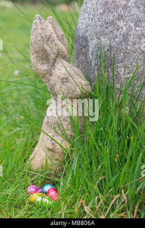 A stone rabbit and chocolate eggs in brightly coloured foil Stock Photo