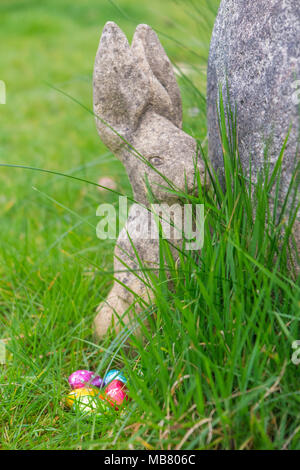 A stone rabbit and chocolate eggs in brightly coloured foil Stock Photo