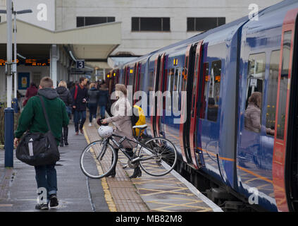 A Cyclist leaving a South West Trains service at Surbiton station with her bicycle Stock Photo