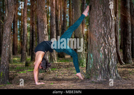 woman practicing yoga outside in the woods, doing a wheel pose. Stock Photo