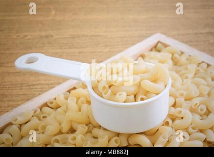 Food and Cuisine, Uncooked and Dried Elbow Macaroni or Gomiti Pasta in Plastic Measuring Cup. Stock Photo