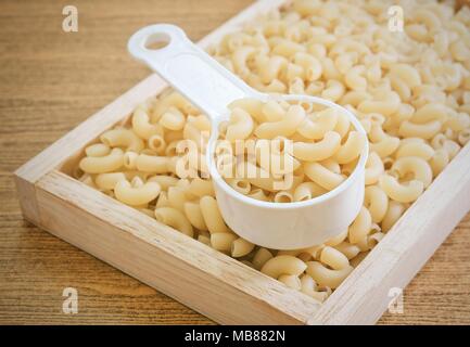 Food and Cuisine, Uncooked and Dried Elbow Macaroni or Gomiti Pasta in Plastic Measuring Cup. Stock Photo