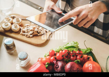 Large snapshot of details, vegetables and a tablet in the hand of a young guy Indoor, studio shot Stock Photo