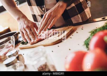 Man cooks meat, marinades in spices. Indoor, kitchen home interior, studio shot. Stock Photo