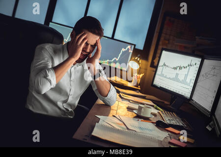 Young bearded man trader at office sitting at table having headache painful touching head Stock Photo