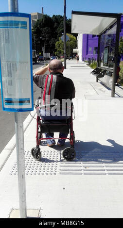 Old man with walking aid waiting for bus Stock Photo