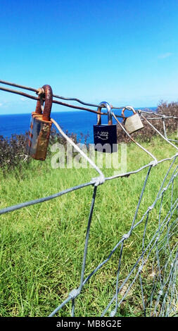 Padlocks on wire fence with ocean in background Stock Photo