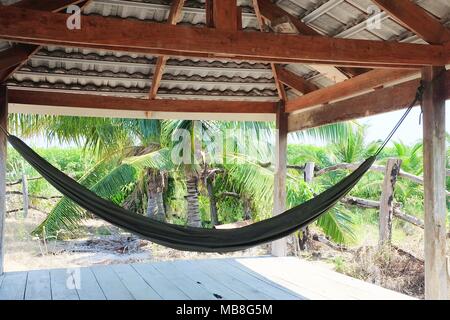 Relaxation Concept, The Hanging Hammock in Coconut Palm Garden. A Sling Made of Fabric Suspended Between Two Poles Used for Swinging, Sleeping or Rest Stock Photo