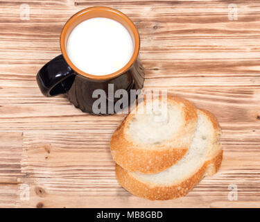 Cream top organic whole milk in ceramic cup and sliced crusty country style round organic french bread Stock Photo