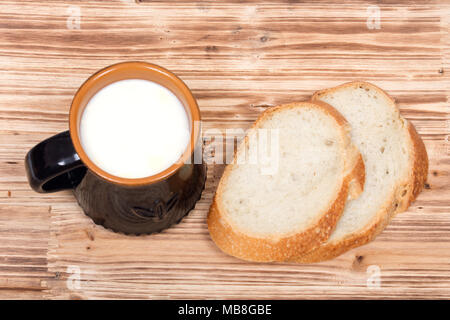 Cream top organic whole milk in ceramic cup and sliced crusty country style round organic french bread Stock Photo