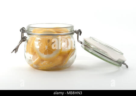 A jar with a lid with yellow lemons, covered with sugar, view on the side. Stock Photo