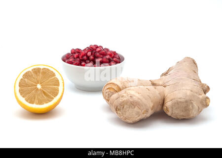 Lemon, a cup of pomegranate seeds and ginger on a white background. Stock Photo