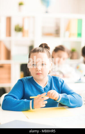 Cute schoolgirl sitting at table and studying Stock Photo - Alamy