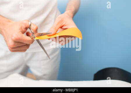 Physiotherapist prepares and cuts kinesio taping. Stock Photo