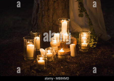 Many burning candles on ground. Beautiful place for outside wedding ceremony in wood. Stock Photo