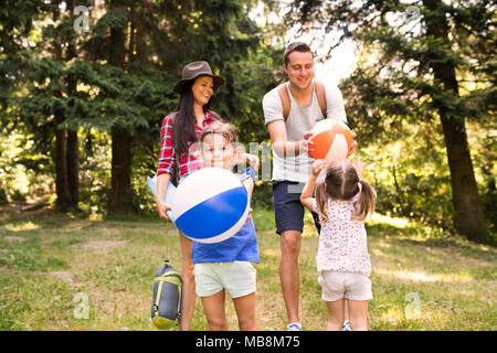 Beautiful young family with daughters going camping in forest. Stock Photo