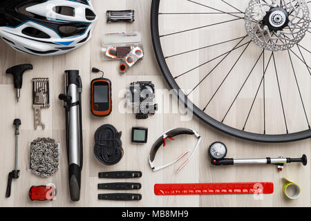 Photo of bicycle objects on wooden background. Wheel, steering wheel, seat, helmet, tire, sunglasses, reflective tape. Stock Photo