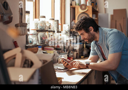 Young woodworker using a tablet in his workshop Stock Photo
