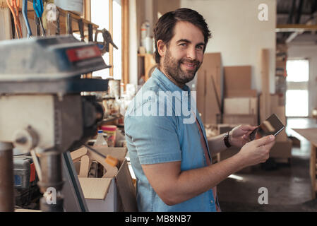 Smiling artisan using a tablet in his carpentry workshop Stock Photo