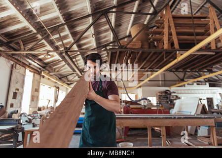 Skilled woodworker examining a wooden plank in his workshop Stock Photo