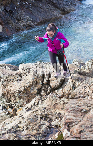 Woman walking over rocks at Fairy Pools, river Brittle, Isle of Skye, Scotland, UK in March Stock Photo