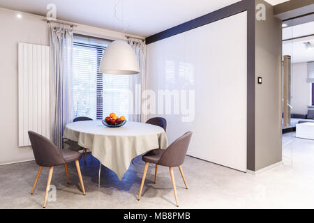 Simple, spacious, white and brown dining room interior design with small table, chairs, and lamp