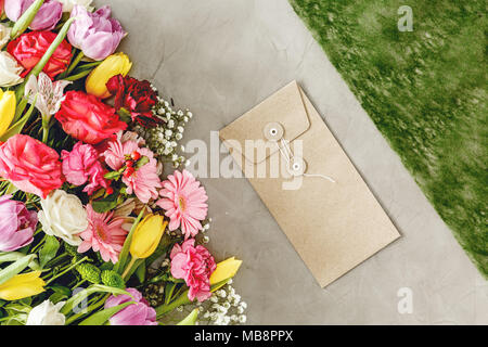 Natural envelope next to colorful flowers on a florist's worktable before valentine's day Stock Photo