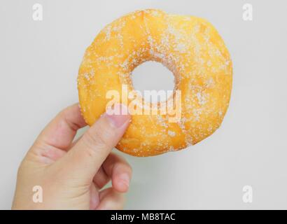 Food and Bakery, Hand Holding Delicious Fresh and Sweet Donut with Sugar Toppings on White Background. Stock Photo