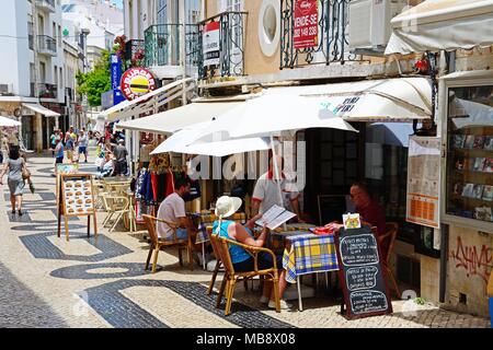 Tourists relaxing at pavement cafes along R Lima Leitao in the old town, Lagos, Algarve, Portugal, Europe. Stock Photo