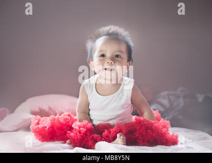 Asian new born baby sit and smile on a  bed in bed room. Stock Photo