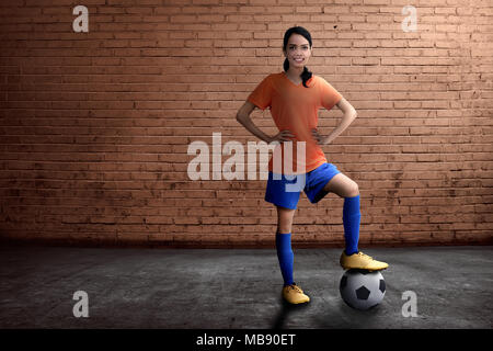 Beautiful asian female footballer standing with ball on her feet at outdoor Stock Photo