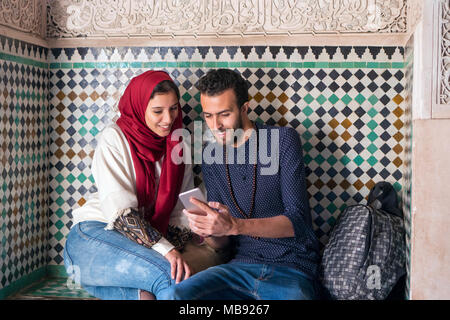 Young Muslim couple smiling and looking at mobile phone Stock Photo