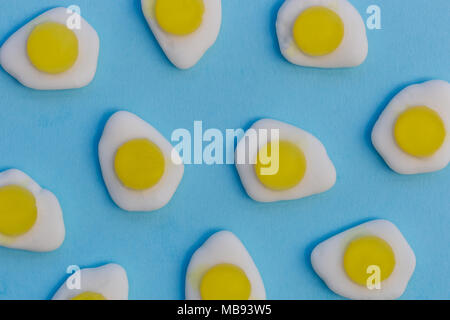 Fried eggs candy sweets overhead on bright blue background Stock Photo