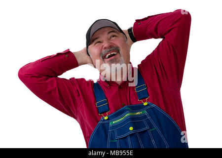 Joyful farmer or worker in bib overalls laughing in delight as he looks up with hands clasped behind his head on white Stock Photo