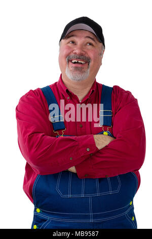 Pleased successful farmer in bib overalls or dungarees standing with folded arms looking up with a happy smile isolated on white Stock Photo