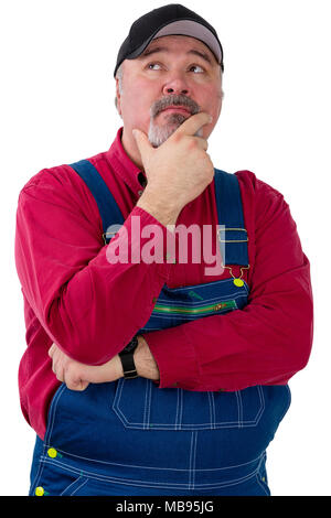 Contemplative farmer, worker or gardener in dungarees and cap standing looking to the side with his hand to his chin isolated on white Stock Photo