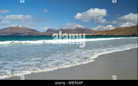 Waves rolling onto the deserted beach at Luskentyre on The Isle of Harris in spring with snow on the hills in the background. Stock Photo