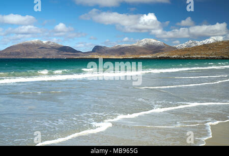 Waves rolling onto the deserted beach at Luskentyre on The Isle of Harris in spring with snow on the hills in the background. Stock Photo