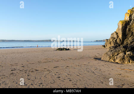 Lone jogger on Castle Beach, Tenby, Pembrokeshire, Wales in the early morning sunshine on a clear day Stock Photo