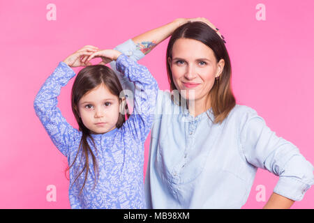 Funny woman and kid over pink background. Happy family playing in home Stock Photo