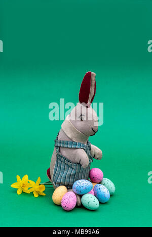 Vintage toy rabbit, bunny, with a pile of chocolate easter eggs. Stock Photo