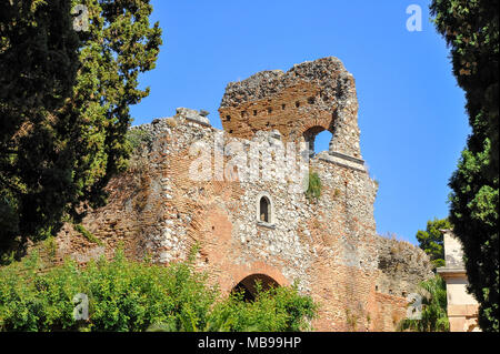Picturesque view of the Ancient theatre of Taormina (Teatro antico di Taormina), Sicily. Crumbling brickwork framed by trees and blue sky background Stock Photo