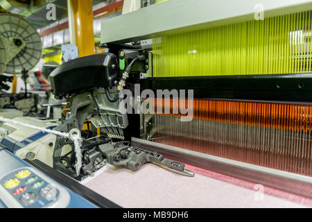 weaving loom at a textile factory, closeup. industrial fabric production line Stock Photo