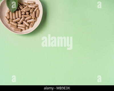 Capsule pills in a plate on green background Stock Photo
