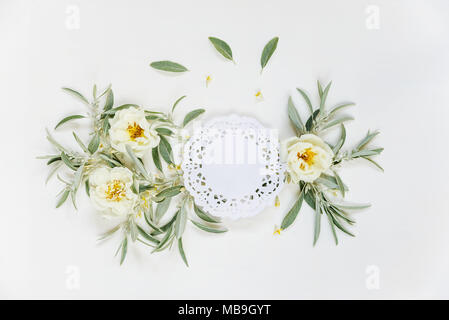 Decorative composition in retro style of vintage white paper napkin and white wild rose flowers with green leaves on white background. Top view, flat  Stock Photo